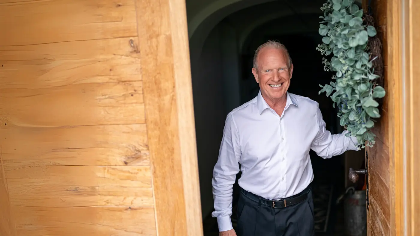 Dr. Spitzbart öffnet lächelnd eine Holztür